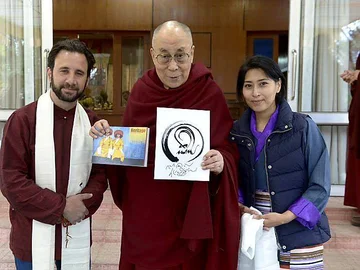 His Holiness the Dalai Lama holding the Himalayan Elders Project logo