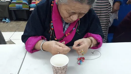 Himalayan elder engaged in a craft activity, threading beads