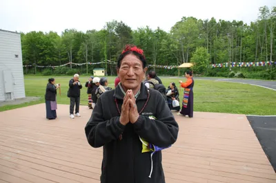 Elder in meditation outdoors with prayer flags