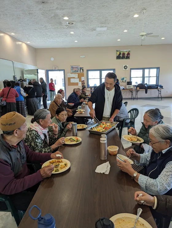 Volunteer serving a communal meal to seated elders