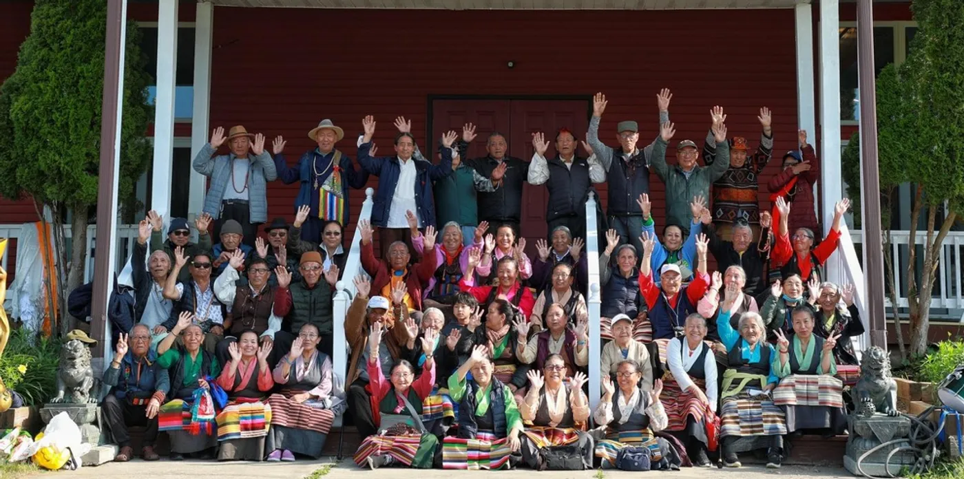 Himalayan elders waving together at a group retreat