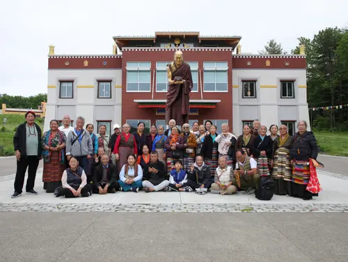 Group outing to Ithaca — elders pose in front of a Buddhist statue